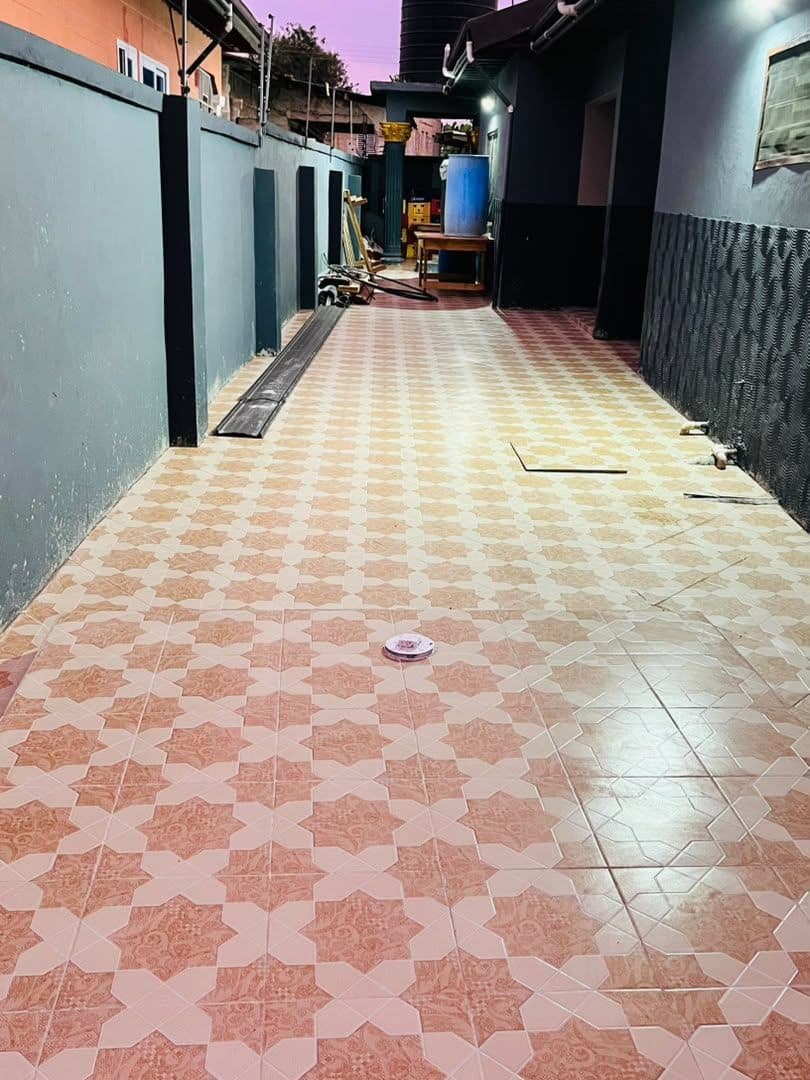 A finished Ibradu exterior walkway laid in a patterned star-motif floor tile running between two painted boundary walls